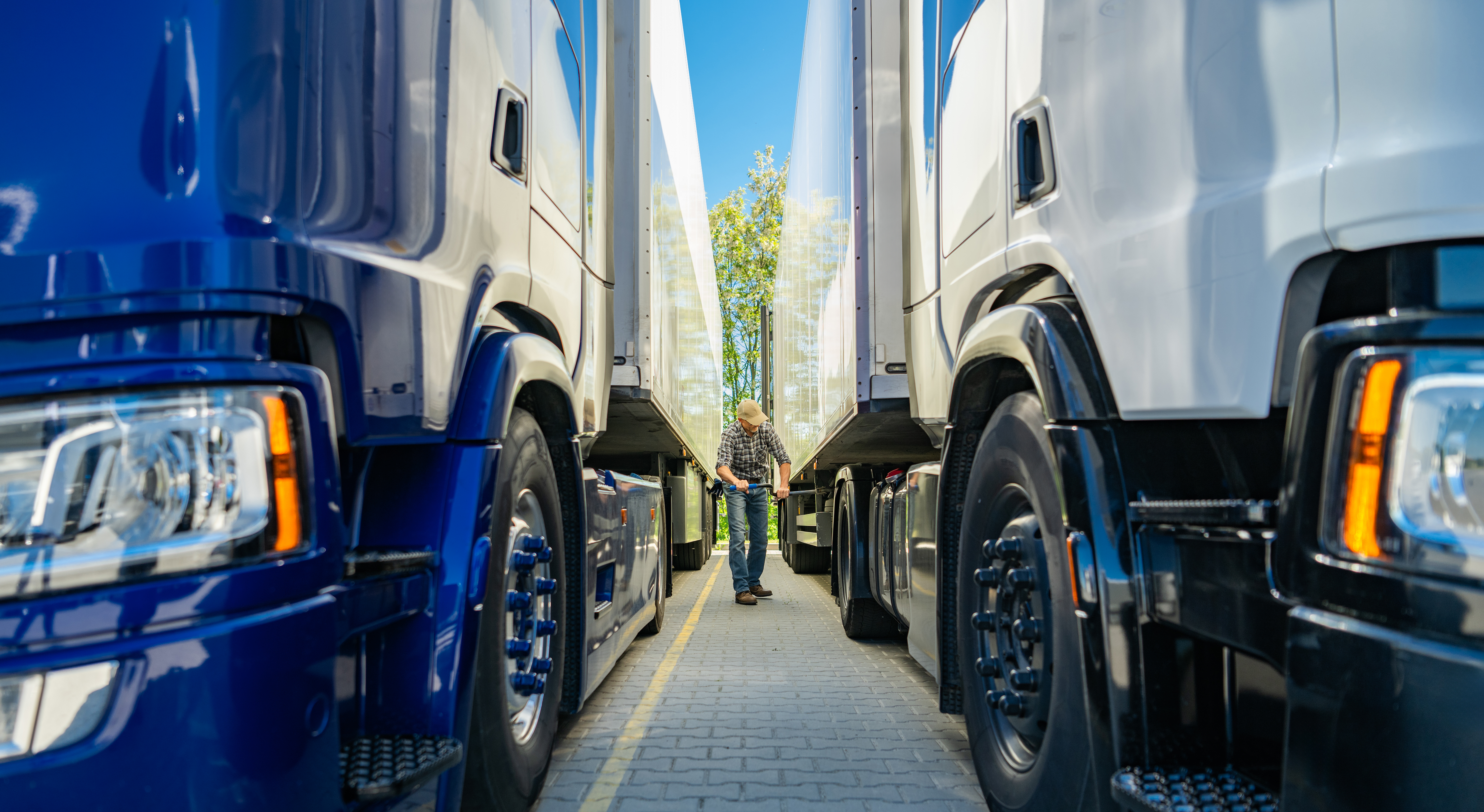 two large semi trucks parked closely together in a transportation yard during daylight hours
