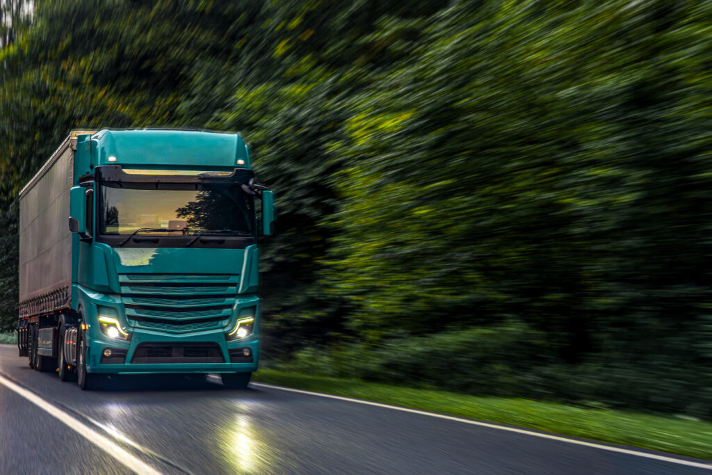 emerald green truck on forest highway. modern power of transport.